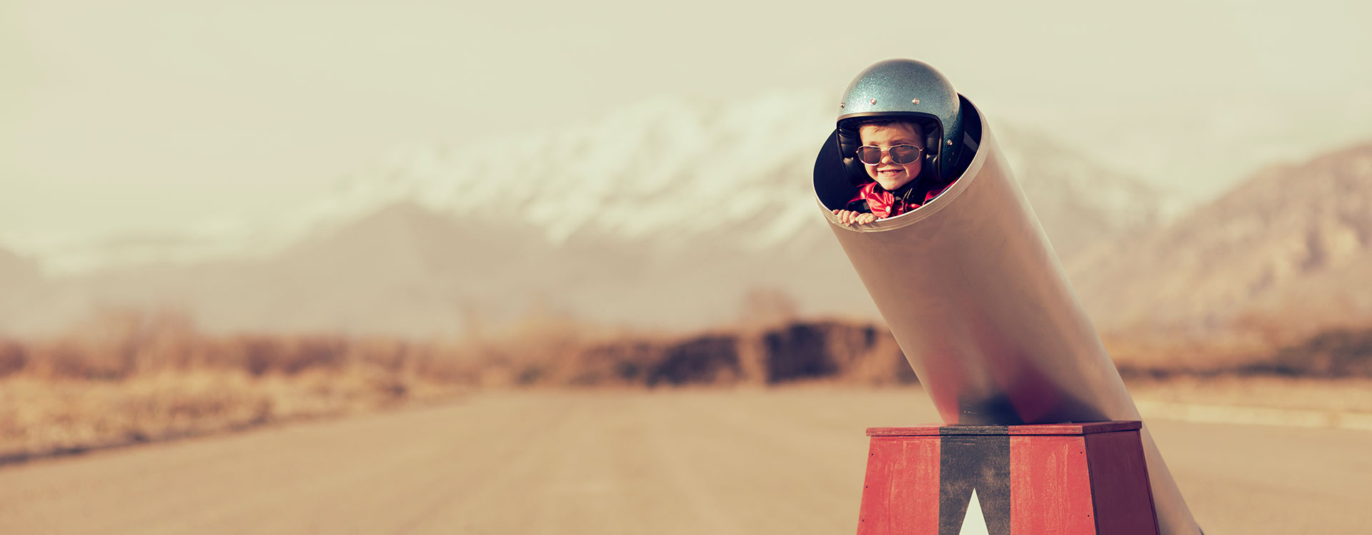 Foto eines kleinen Jungen mit Helm, der in einer nach oben gerichteten Kanone liegt - HEUTE UND MORGEN