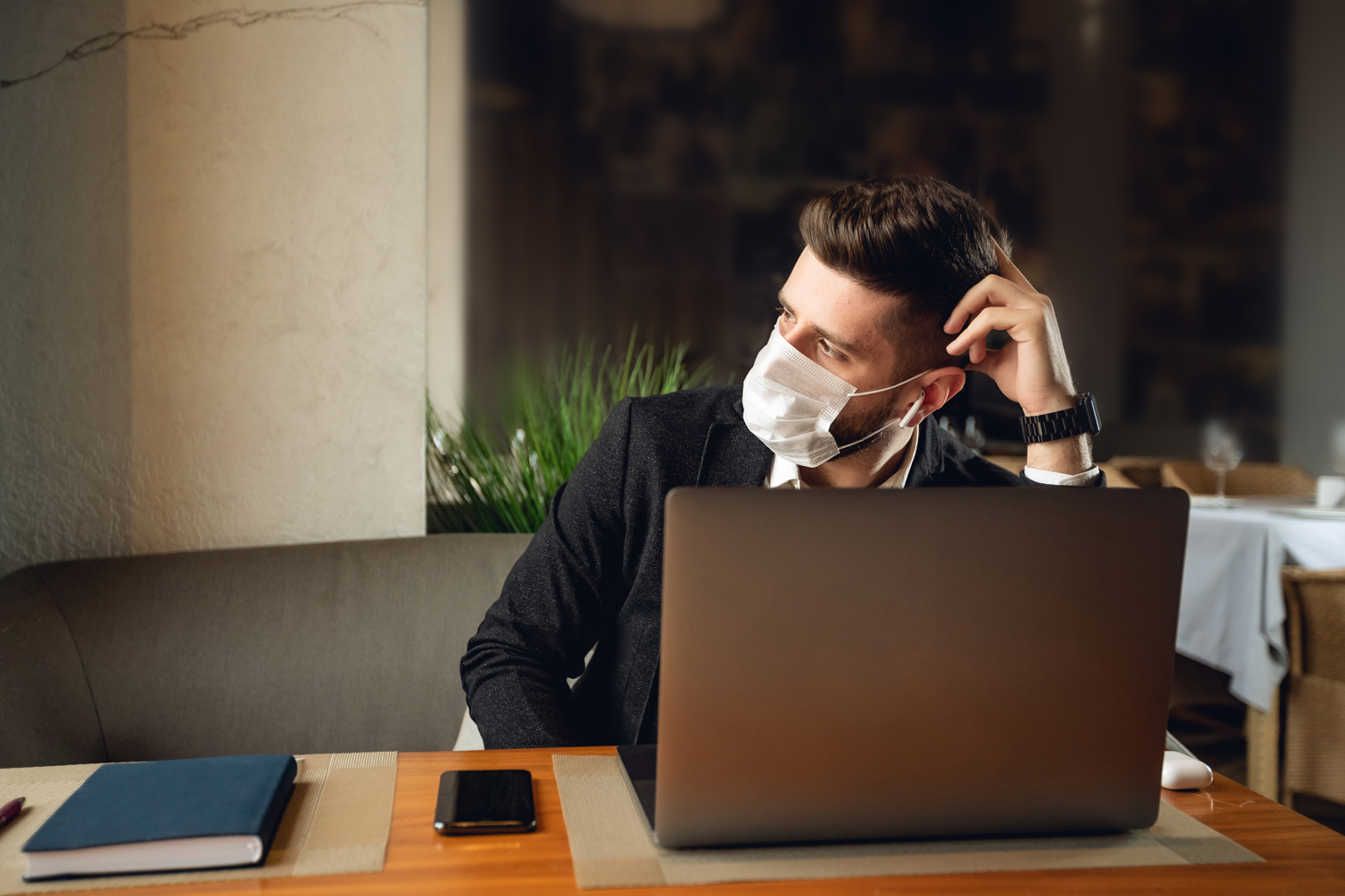 Mann mit Maske vor Laptop